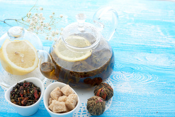 Ripe lemon, cinnamon and fruit drink in glass teapot on wooden