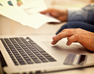 Businessman sitting at table with laptop and documents