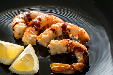 Fried shrimps with lemon wedges on the black background