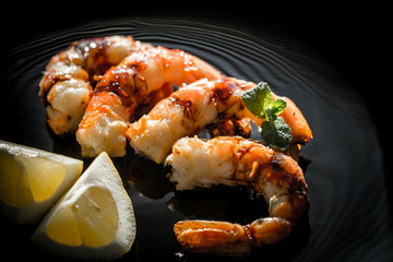 Fried shrimps with lemon wedges on the black background