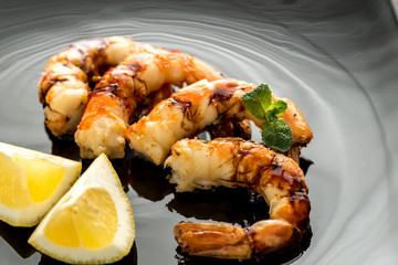 Fried shrimps with lemon wedges on the black background
