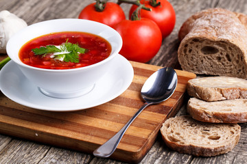 Borsch with bread on a wooden background.