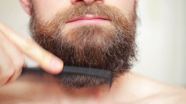 Сare beard - man combing his mustache and beard