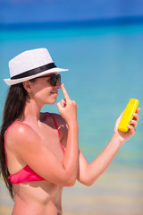 Young happy woman applying suntan lotion on her nose on white