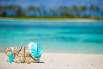 Straw bag, blue hat, sunglasses and sunscreen bottle on tropical
