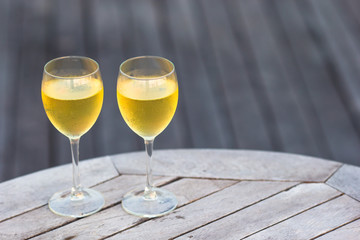Two glasses of tasty white wine at sunset on wooden table