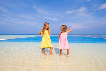 Naklejka premium Two cute little sisters have fun together near swimming pool