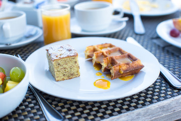 Delicious waffles, cake, coffee and juice served for breakfast