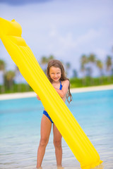 Adorable happy girl with inflatable air mattress on white beach