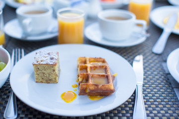 Delicious waffles, cake, coffee and juice served for breakfast