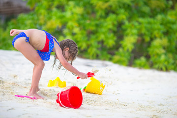 Adorable little girl playing with beach toys during tropical