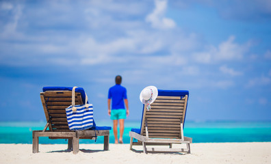 Lounge chairs with bag and hat on tropical beach at Maldives