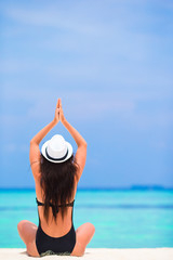 Healthy young woman in hat sitting in yoga position meditating