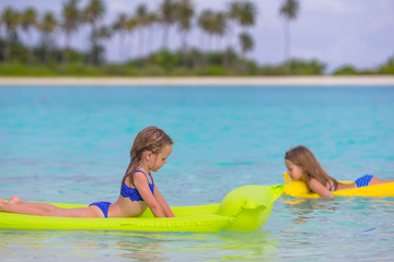 Fototapeta na wymiar Adorable little girls on air inflatable mattress in the sea
