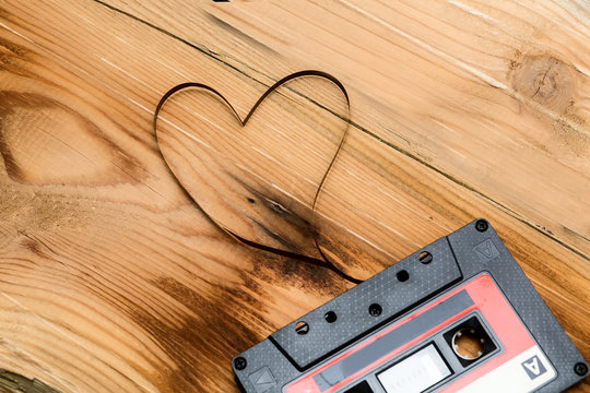 Vintage audio cassette with loose tape shaping two hearts on a w