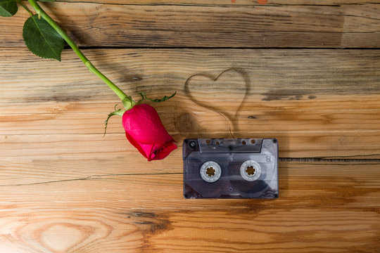 rose and vintage audio cassette with loose tape shaping one hear