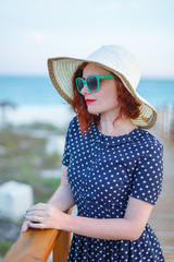 Red-haired girl in a hat and sunglasses