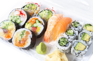 Assorted sushi rolls and nigiri in a transparent plastic tray ag