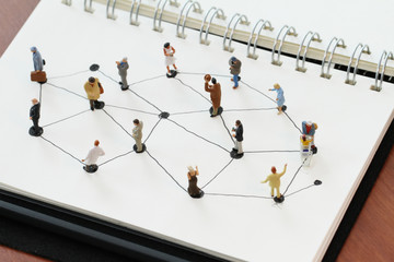 close up of miniature people with social network diagram on open