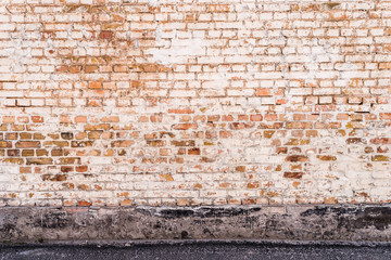 Aged grunge brick wall with part of asphalt road