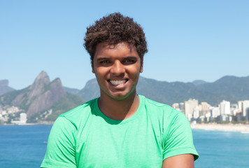Fröhlicher Latino im grünen Shirt am Strand von Ipanema