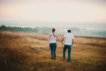 Beautiful couple  comes in a field at sunset, lifestyle-concept