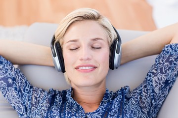 Pretty blonde woman listening music on the couch