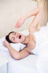 Pretty brunette yawning on bed