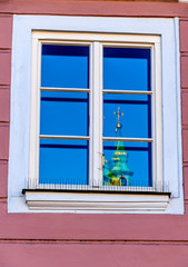 Kirchturm spiegelt sich in einem Fenster