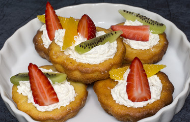 Cupcakes with whipped cream, strawberries, orange and kiwi