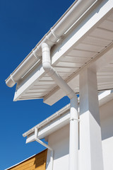 New rain gutter on a white home against blue sky © brizmaker