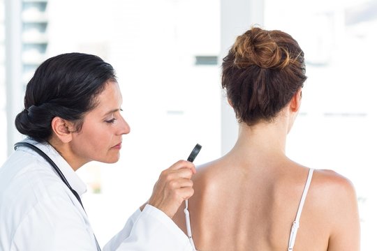 Doctor examining patient with magnifying glass