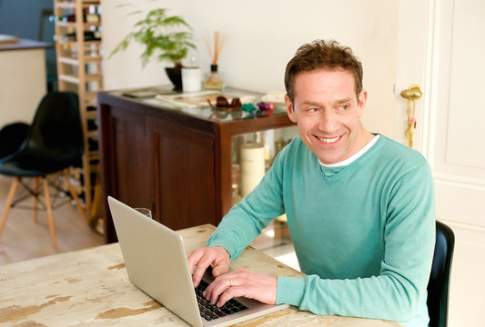 Happy Middle Aged Man Using Laptop At Home