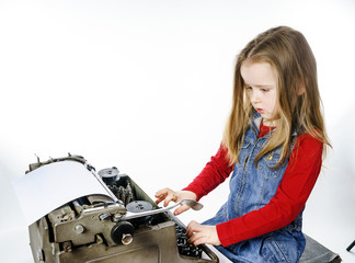 Obraz na płótnie Canvas Cute little girl typing on vintage typewriter keyboard