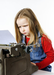 Fototapeta na wymiar Cute little girl typing on vintage typewriter keyboard