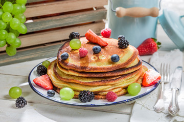 Tasty pancakes with maple syrup and fruits