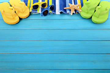 Beach background border summer vacation holiday with flip flop sandals sunglasses accessories on old blue wood planked decking in a row line space for copy text photo
