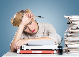Obraz premium Desk. A bored office worker sitting behind a large stack of