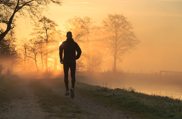 Trail runner during a foggy, spring sunrise in the countryside.