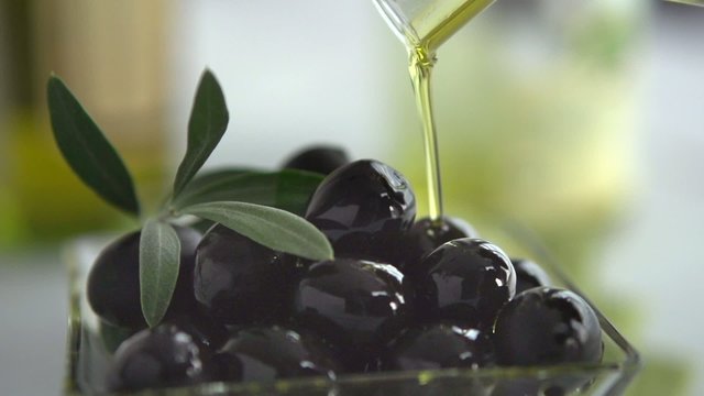 Extra Virgin Olive Oil Pouring on Black Olives