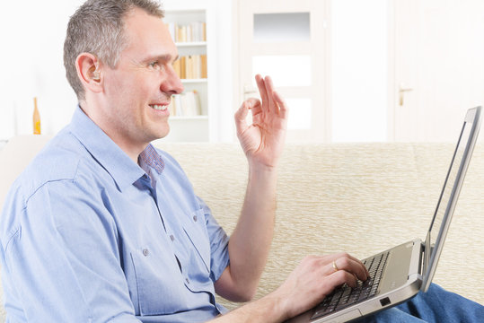 Deaf man using sign language with laptop