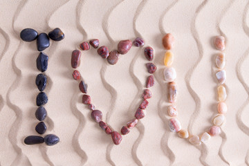 I Love You in colorful stones on golden beach sand