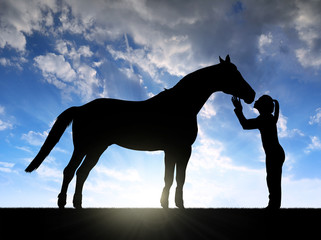 Silhouette of a girl giving a kiss horse in sunset