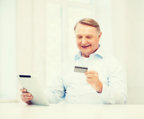 old man with tablet pc and credit card at home