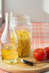 Olive oil bottle, glass with pasta and tomatoes