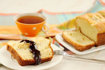 Mascarpone cake slice, cup of tea in orange teacup, blueberry ja