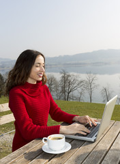 Woman working on laptop at an oudoor restaurant