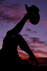 silhouette of womans legs with cowboy hat up on one foot other d