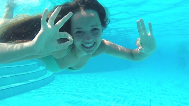 Beauty young woman swimming underwater in swimming pool