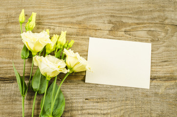 Empty postcard and colorful flowers on wooden background